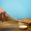 A small bottle for drizzling olive oil, fitted with a cork pouring spout and embodying the Benefield Spencer signature white filigrana cane pattern. Shown being used in the kitchen 