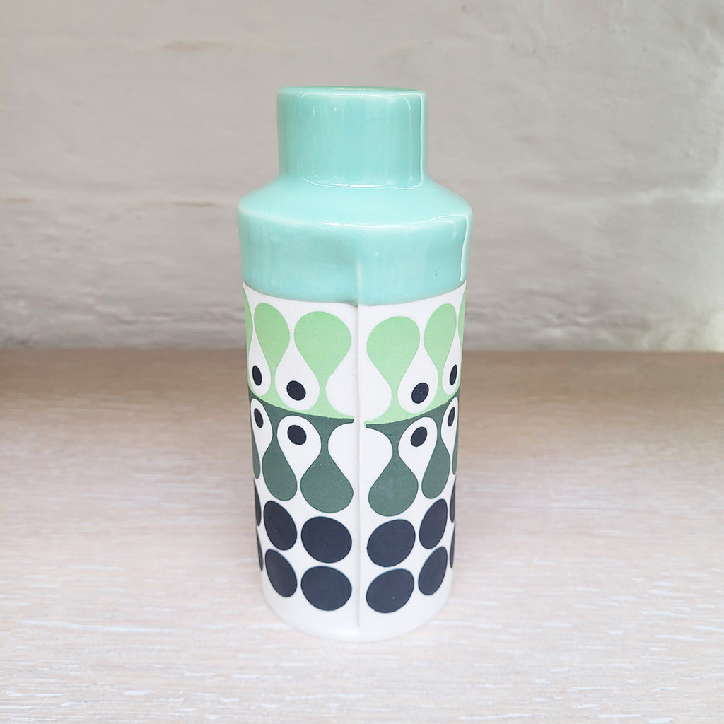 Back view of Cylinder vase by Maree and Paul Allitt this piece is predominently white background with shades of green and black in the pattern