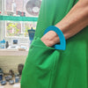 Teal D-shaped bangle inspired by the Bauhaus design movement being worn with a green dress.  Made from linoleum and hand painted by Studio Ditto