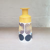 Slab-built porcelain ceramic bottle with predominently white background with black and purple pattern and a yellow top section. Back view